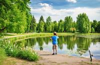 【画像素材】公園の池のほとりで釣りをする少年