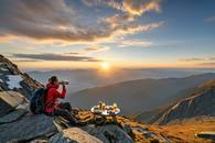 【画像素材】山頂で日の出を眺めながら朝食を食べる登山家